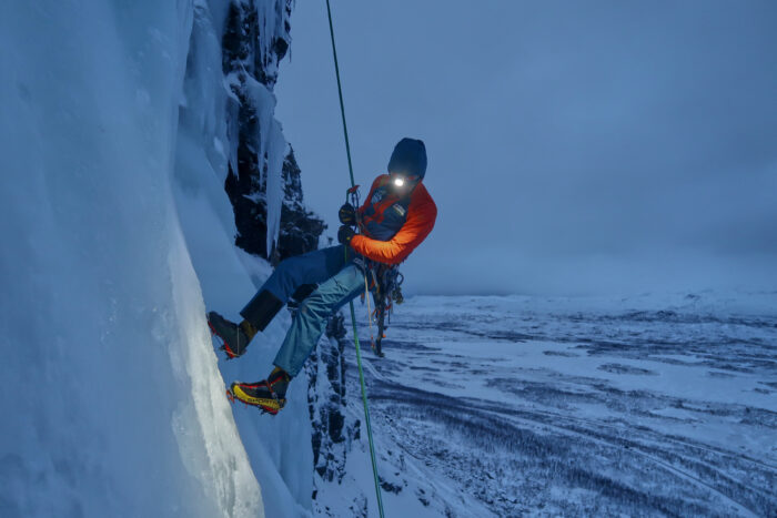 Climber rappeling in dim light.