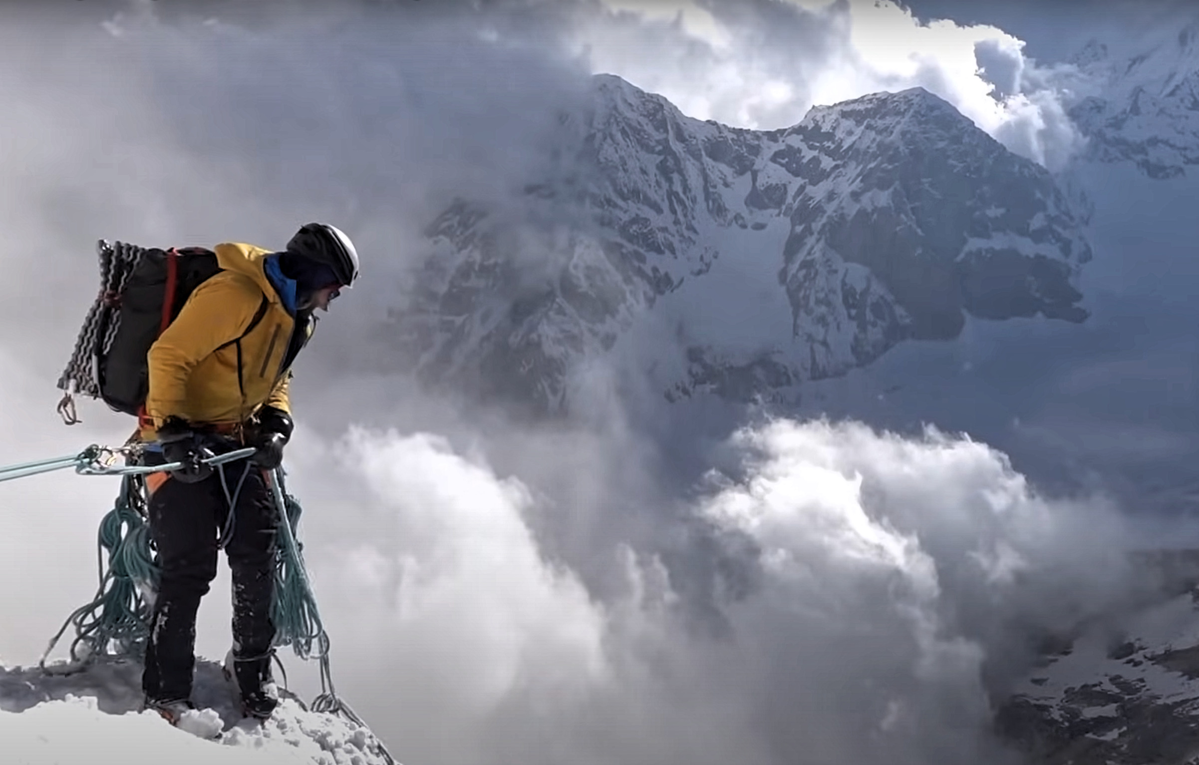 a mountaineer overlooks a cloudy precipice
