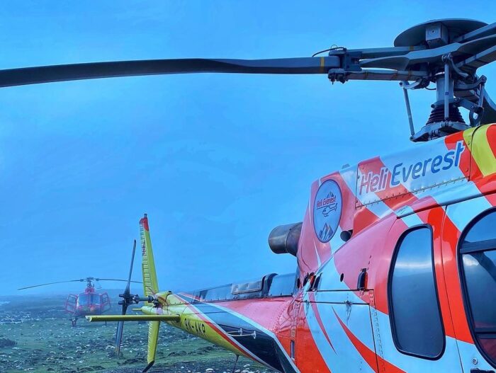 two helicopters grounded on rocky terrain in the fog.