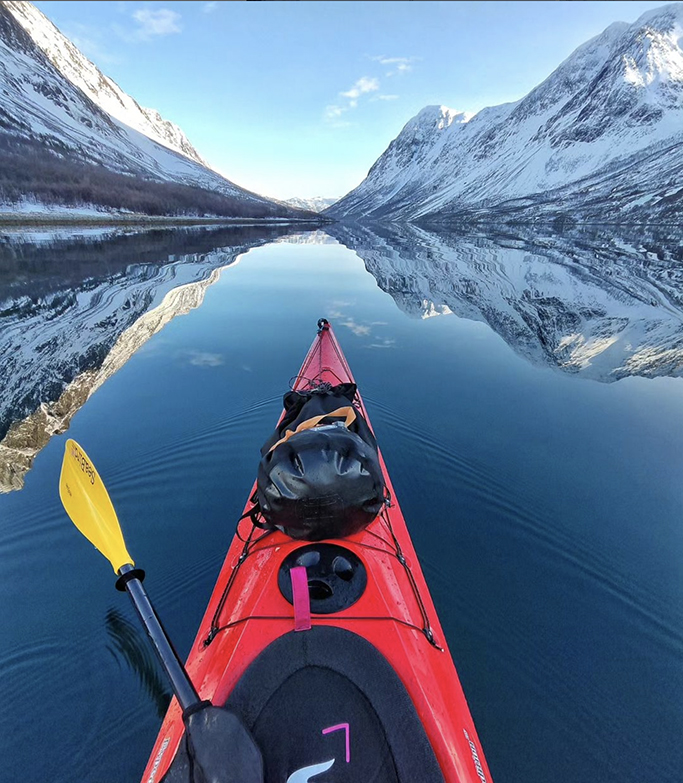 bow of red kayak mirrored in the water