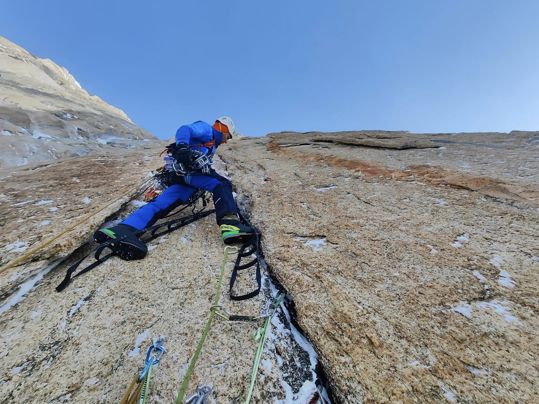 The climber on aid-climbing gear to pass a crack on otherwise smooth granite.