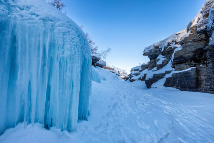 Frozen water looking blue on a snow-covered canyon.