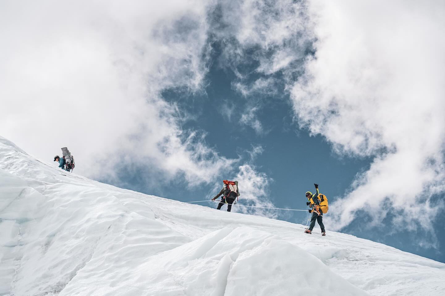 Climbers climb on a snow ramp with the ski behind.