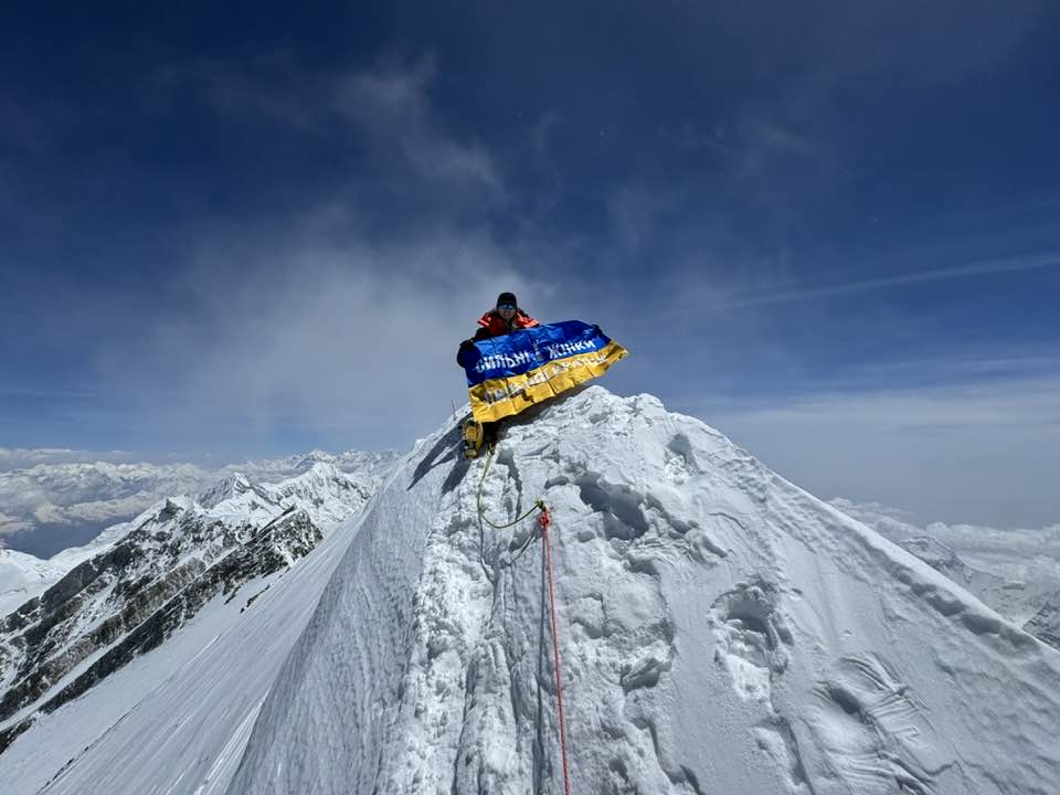 Galay on the summit holding a big Ukrainian flag.