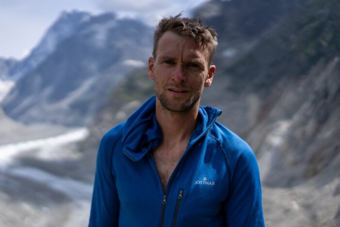Close shot of Howell in a blue fleece, mountains and a glacier behind.