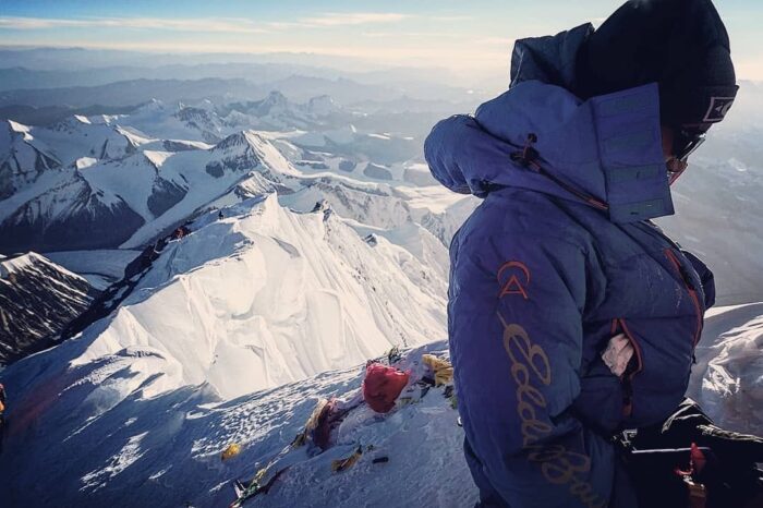 A Sherpa climber looks down on the summit, with the final ridge sections behind him. 