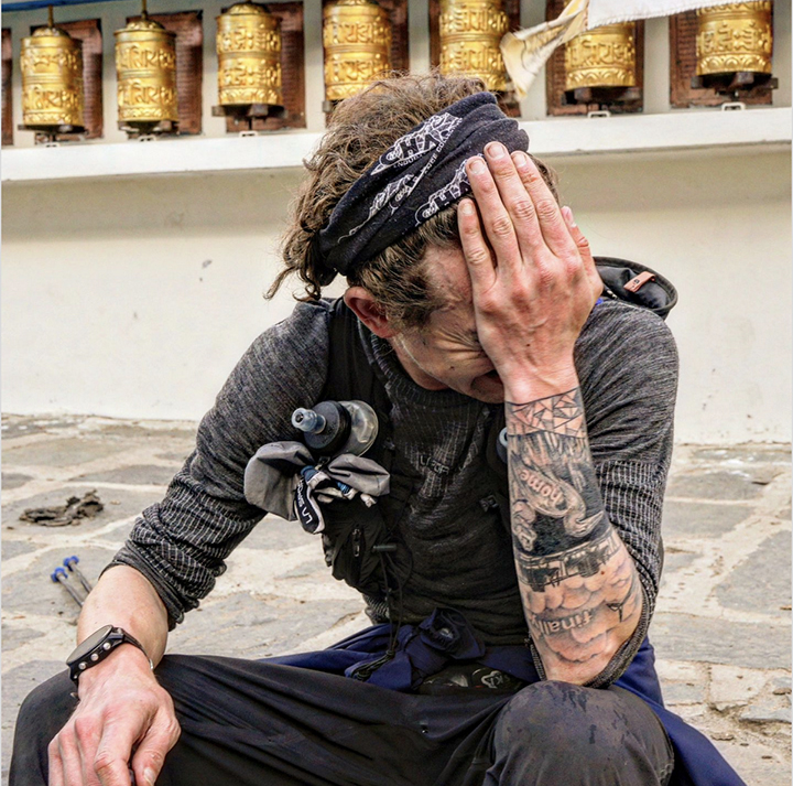 Tattooed man sitting, head in hands