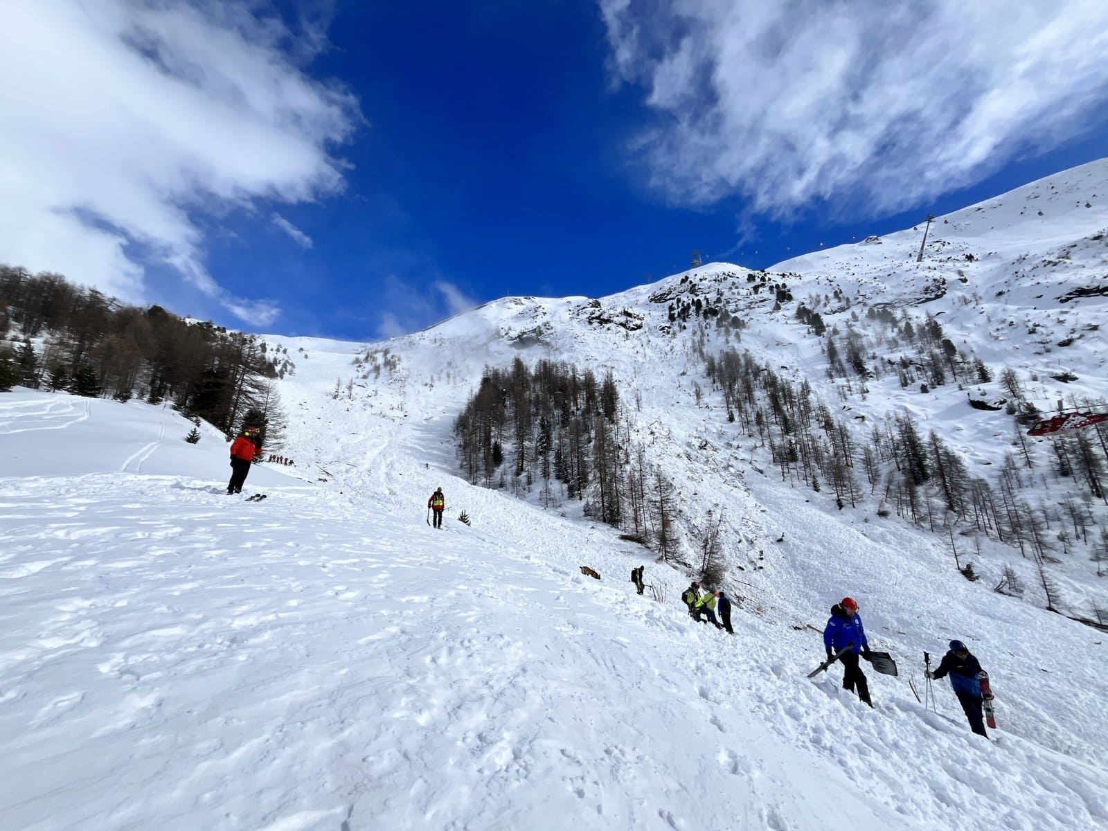 People with shovels at a snow slope.