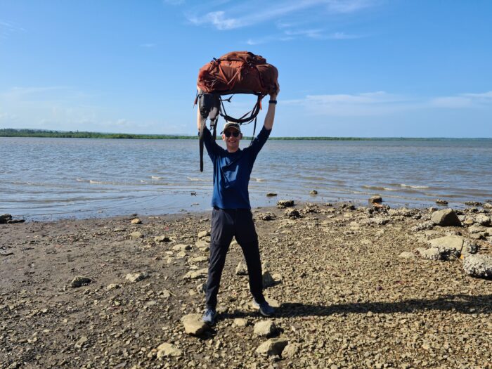 Cristea holds a backpack over his head, at the sea shore