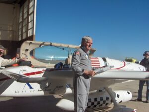 gray-haired pilot in flight suit with aircraft