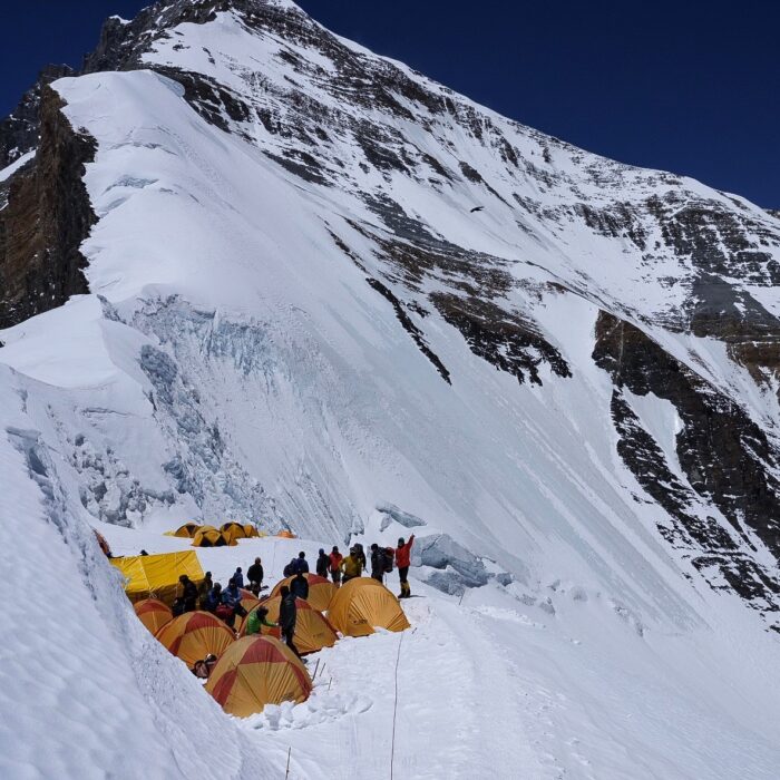 tents in Camp 4 with some climbers outside and the face of Lhotse