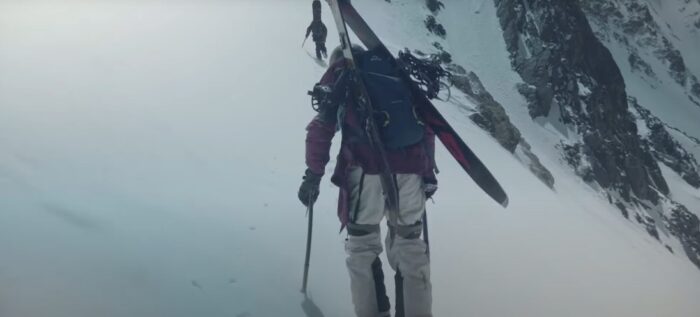 two skiers climbing up a slope