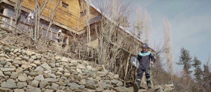 a young boy walks out of his house holding a snowboard