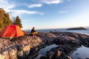man beside orange tent at seaside