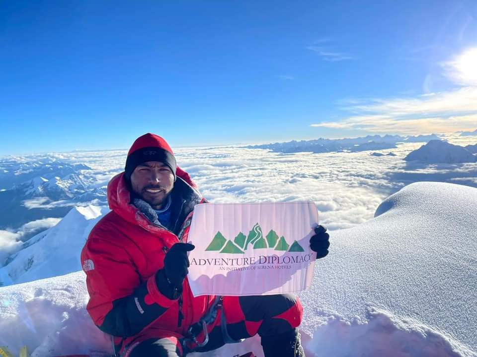 Sirbaz without sunglasses, holding a banner of an undetermined summit.