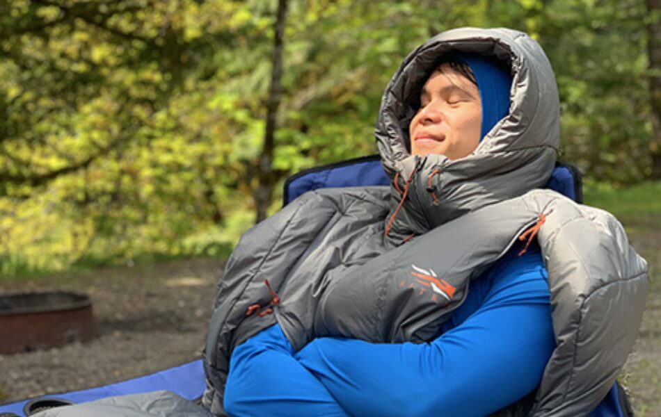 Kirby's partner relaxes in the Sitka Aerolite Sleeping bag, with his arms out.