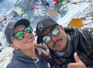 The climbers smile to the camer with sunglasses and caps