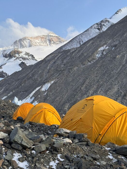 Three tents on rocky ground by a moraine, Everest north side in background
