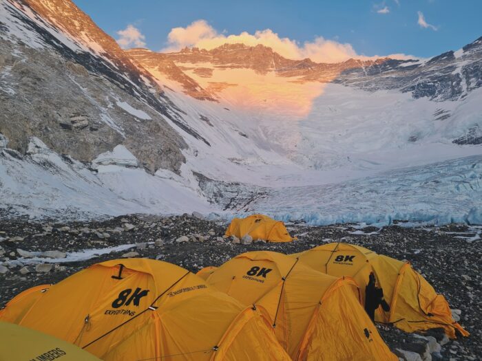 Tents in Camp 2 on rockly, flat ground, and the Lhotse face in background with alpenglow.