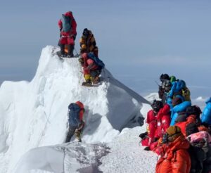 Climbers on Everest summit ridge, a gap on it, a clmiber hangs from the fixed rope and tried to crawl up back to the ridge