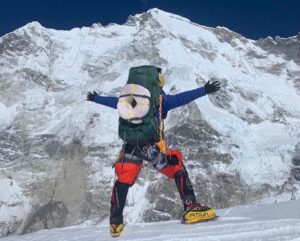 Gelje from the back, opens his arms while carrying rolls of rope on the south face of Cho Oyu