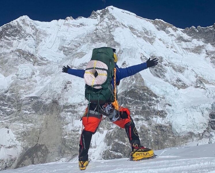 Gelje from the back, opens his arms while carrying rolls of rope on the south face of Cho Oyu