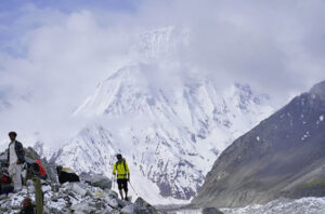 Climbers on a trail with a formidable mountain face behind them.