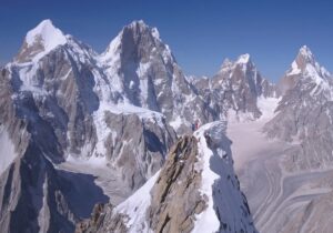 The climber on a peaky summit with other sharp peaks around.