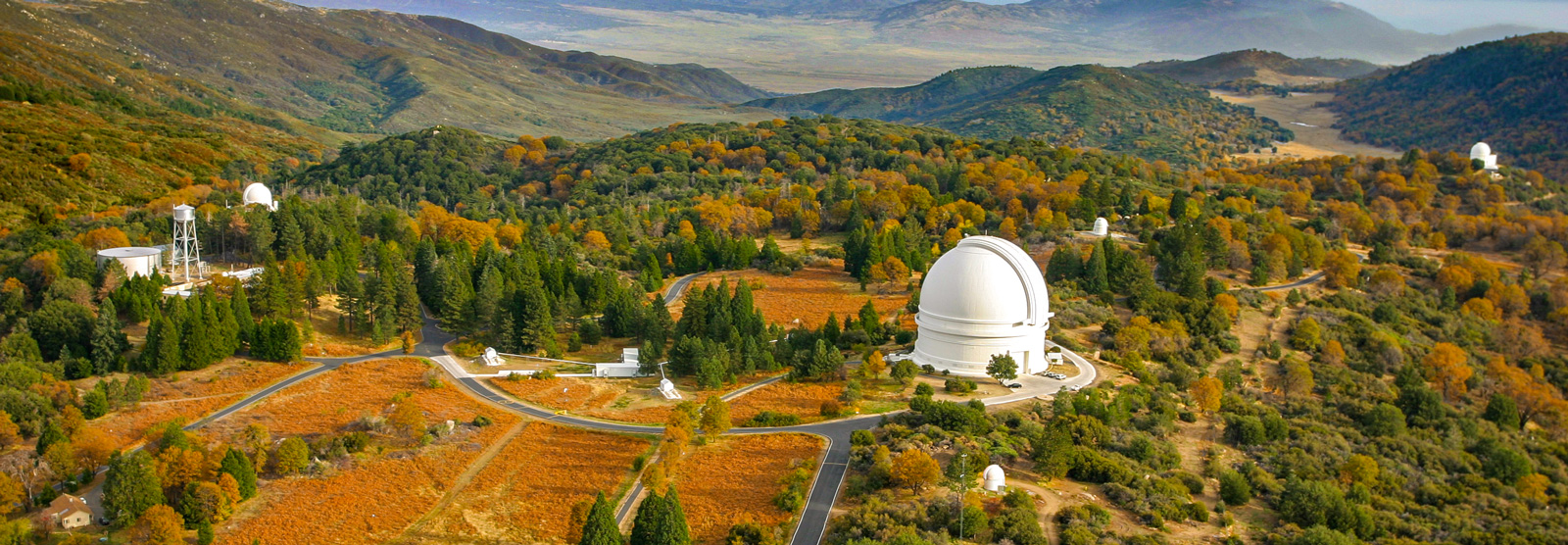 An aerial shot of a collection of domed telescopes nestled in the mountains.