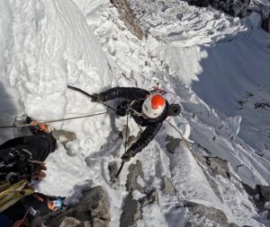 the climber on vertical mixed terrain. leaning on both ice axes with the void at his feet.