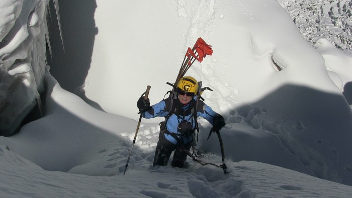 Nives Meroy on a snow-loaded slope, carrying poles to mark the route