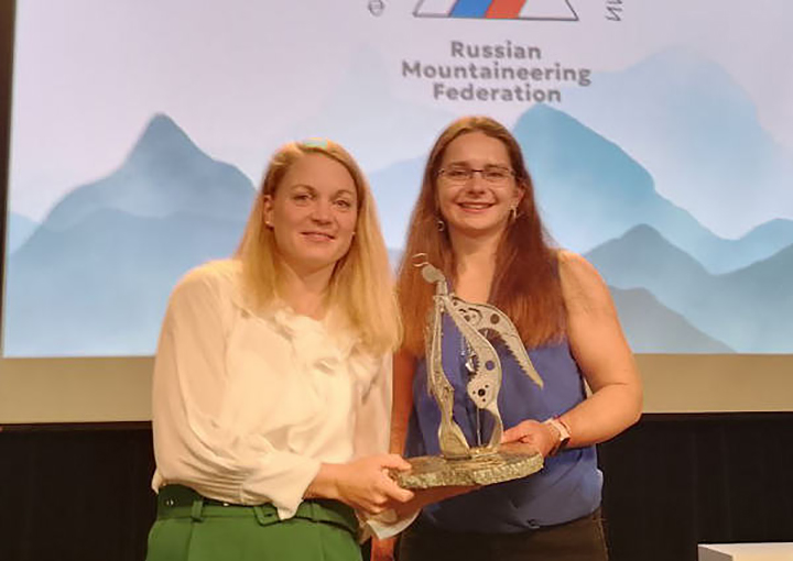 Two women climbers with a trophy on the stage.