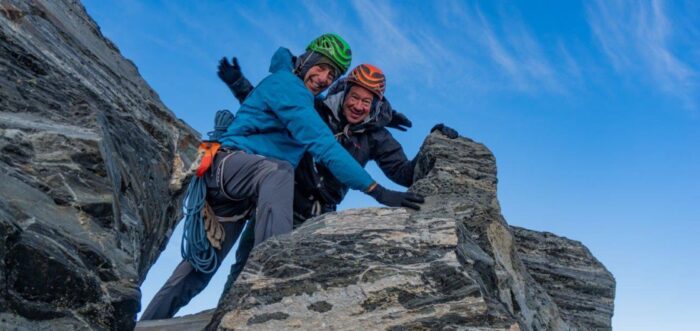 the climbers with helpets on a rocky summit.