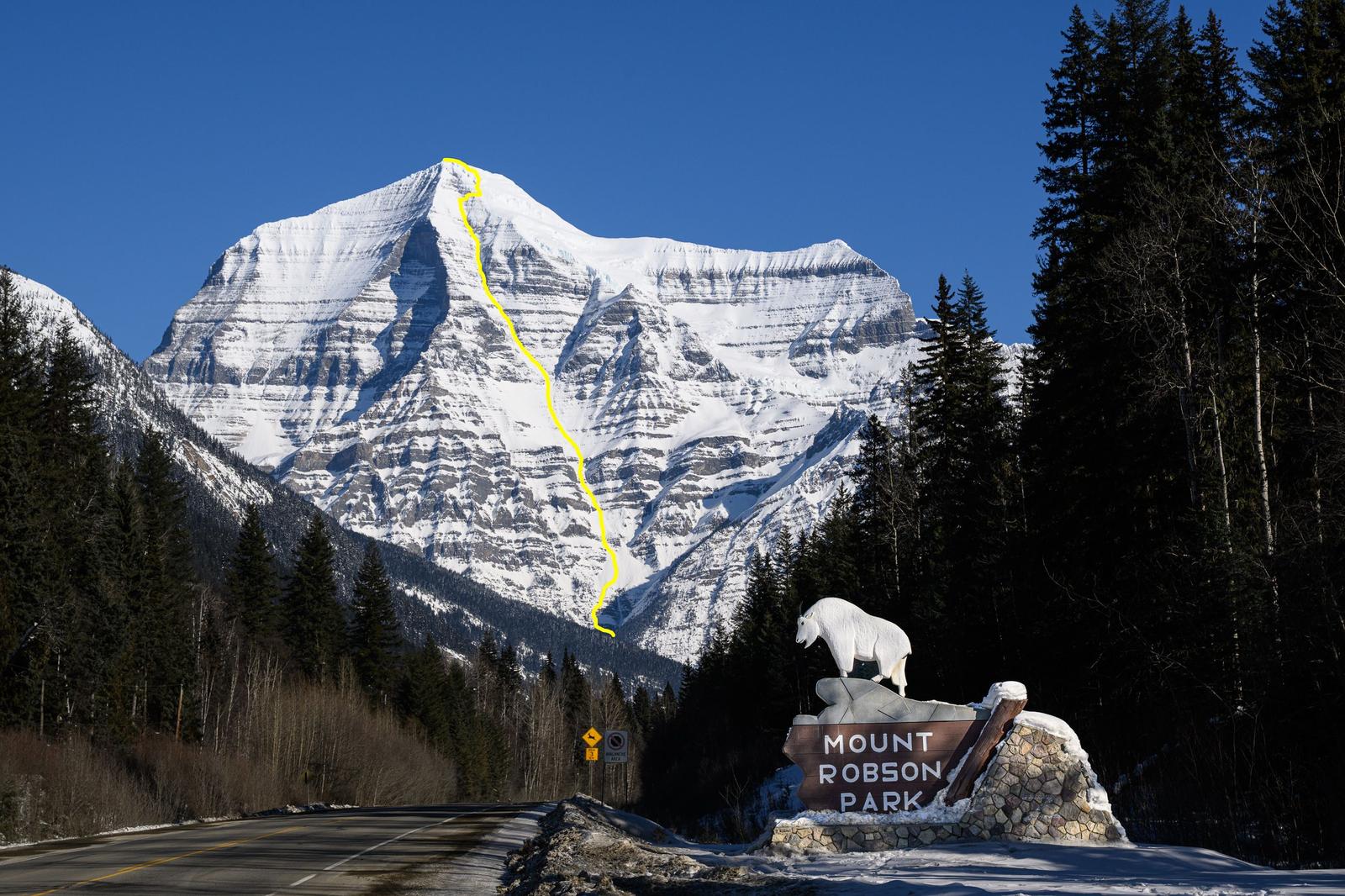 The south face of mount Robson, british Columbia, as seen from a road with a photo point. A ski line is marked in yellow on the face.