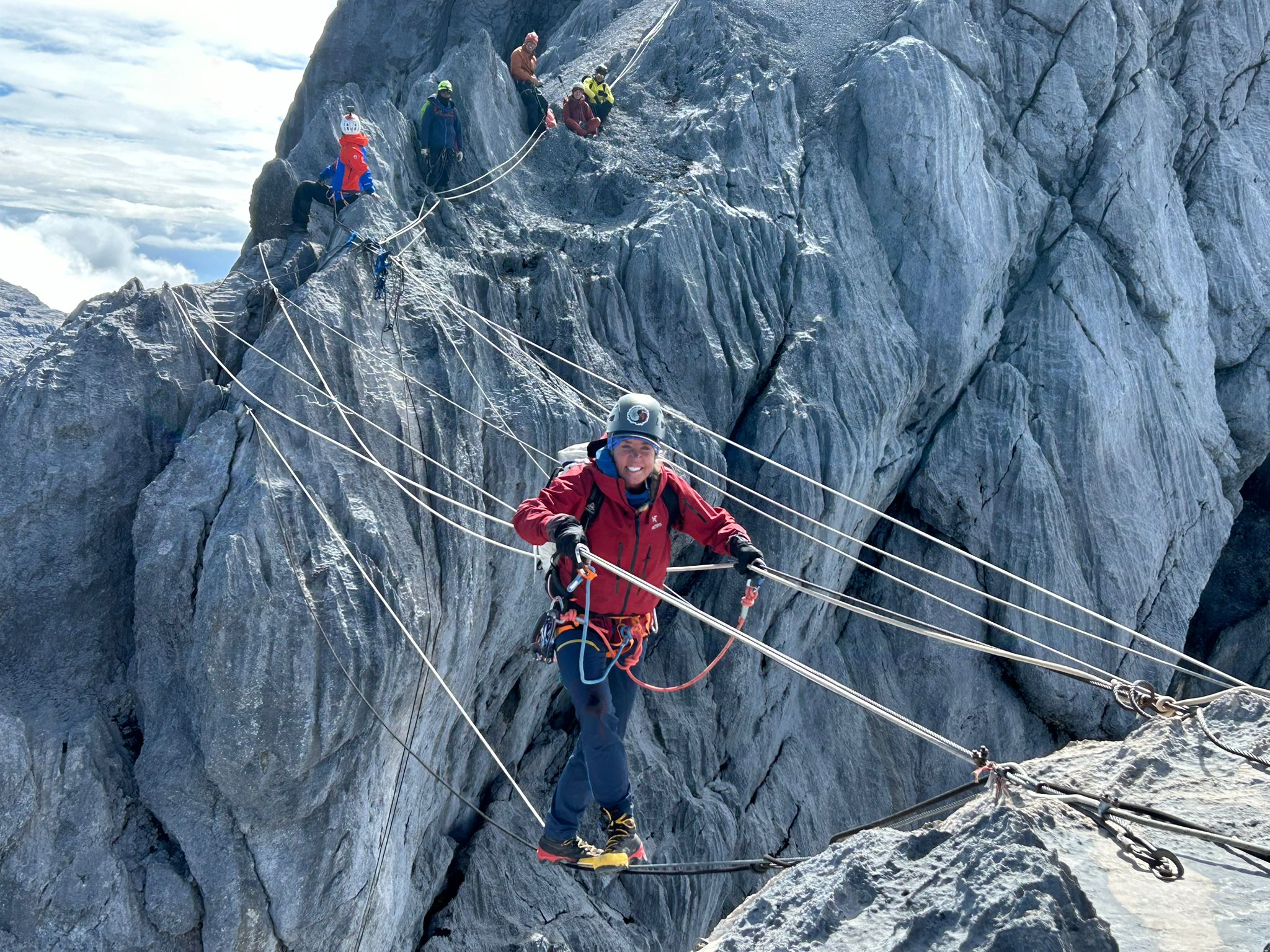 A climber on a traverse across a rock gap, made by several wires