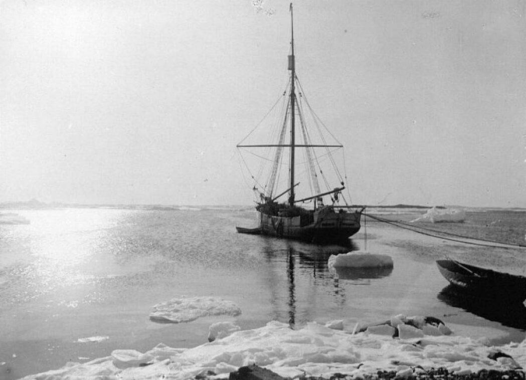 A sloop facing away, with snow and ice in the foreground.