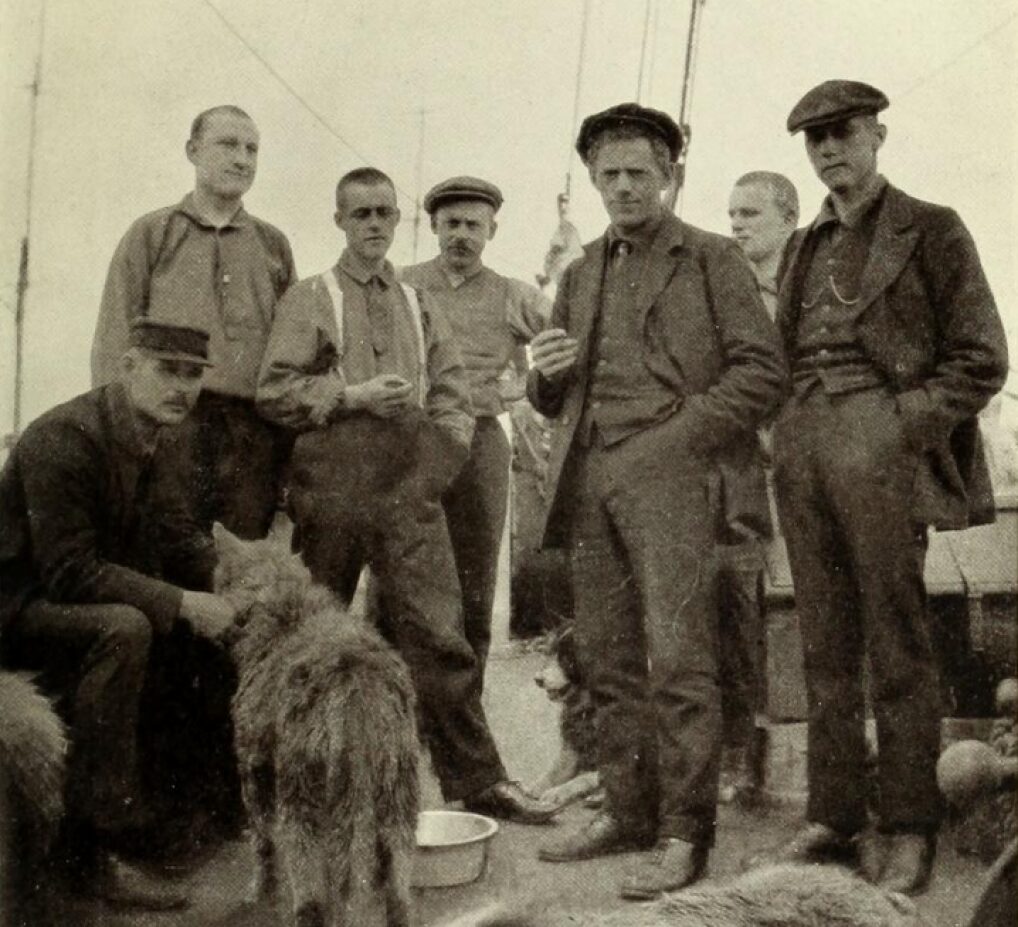 Vintage photograph of seven men and a dog on a ship.
