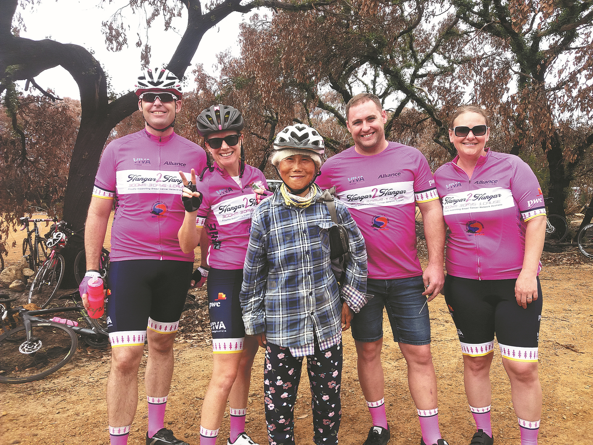 A woman poses with four men in pink shirts.