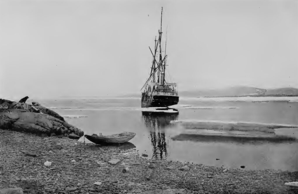 A ship sailing away with a coast in the foreground.