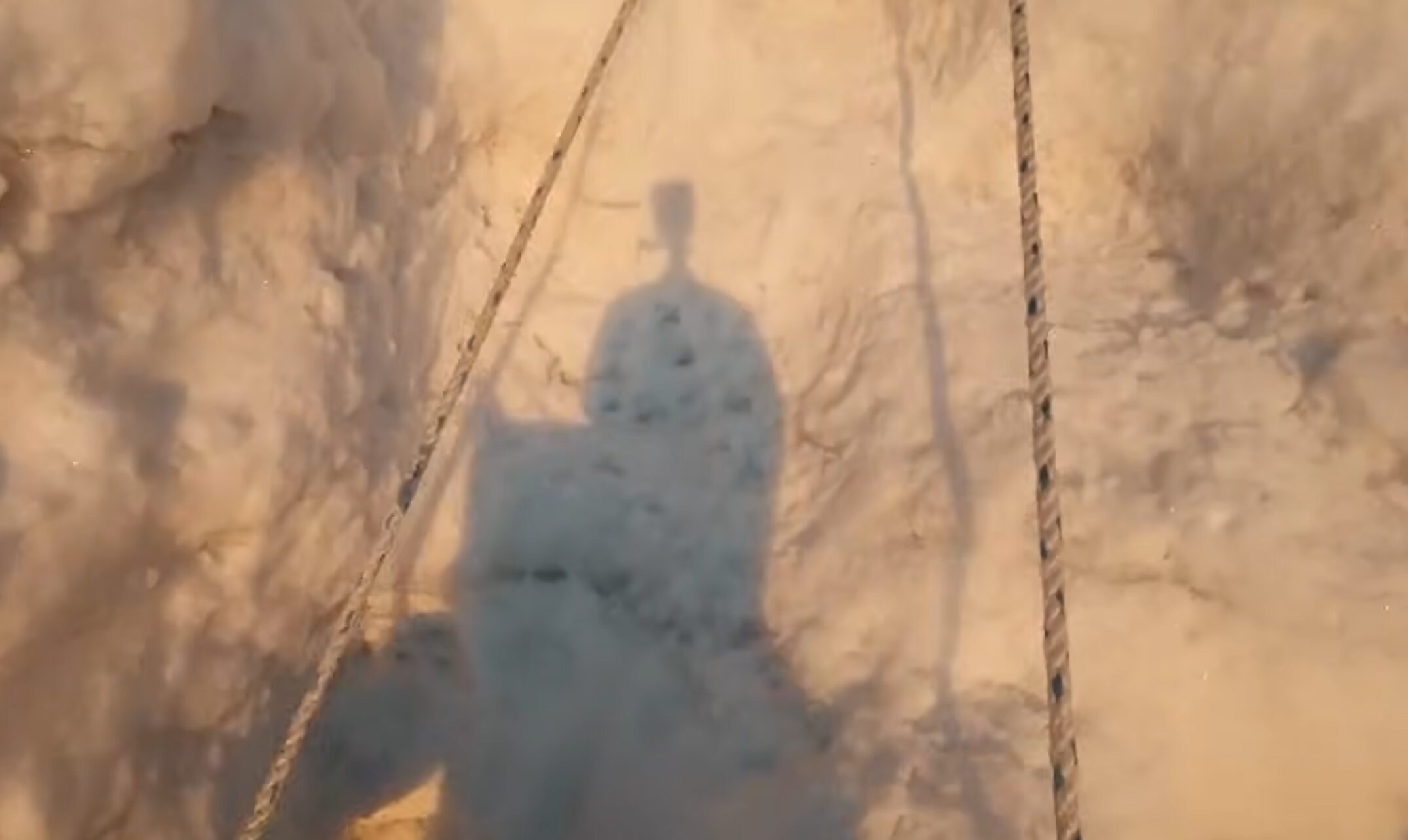 the shadow of a climber with a headcam, on a serac ice and fixed ropes.