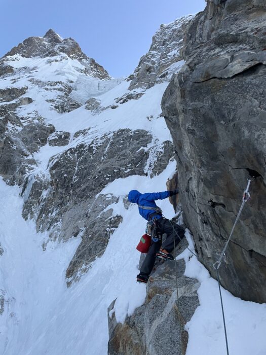 A climber on an overhanging mixed section of a face.
