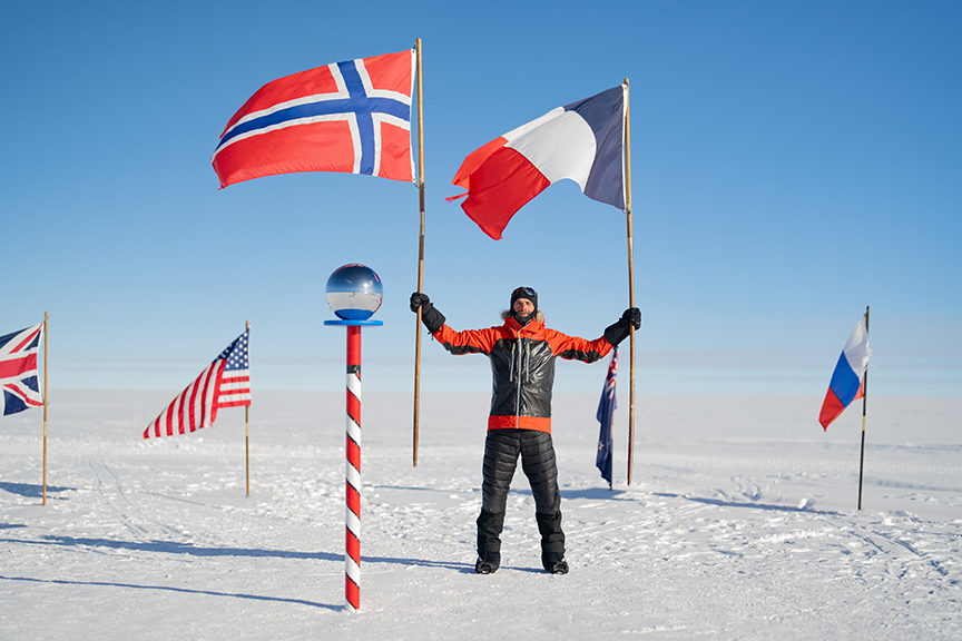 man beside flags at the South Pole