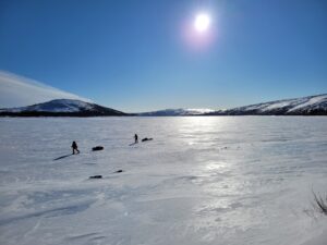 skiers pulling sleds on frozen surface