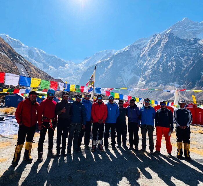 A line of Sherpas standing in front of the chorten at Annapurna Base Camp, with the mountain in background. 