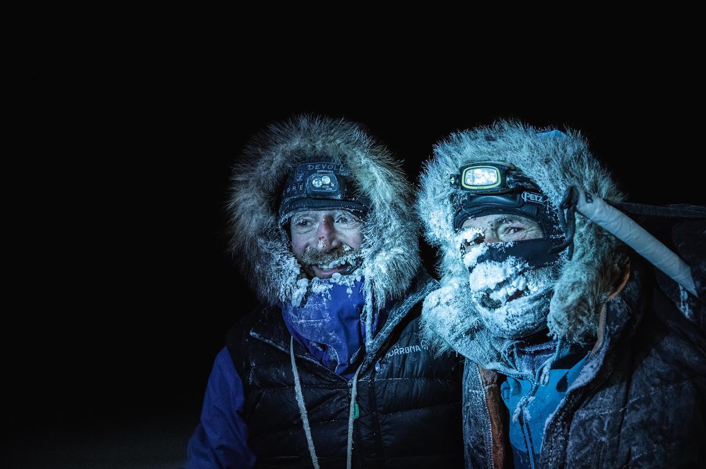 two polar explorers frosted up in the dark