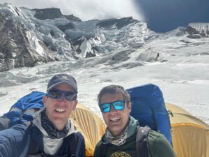 two climbers in front of some tents with Annapurna in background.