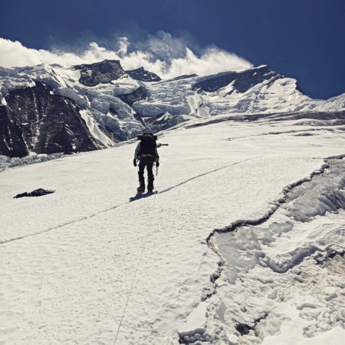 A climber progress on a slab of hard snow/ice, clipped to a fixed rope, on Annapurna.