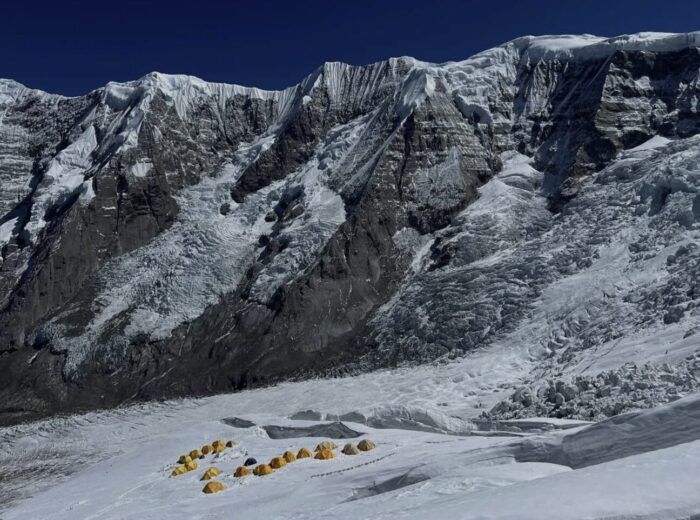 tents pitched together on a glaicer in front of the great couloir of Annapurna. 