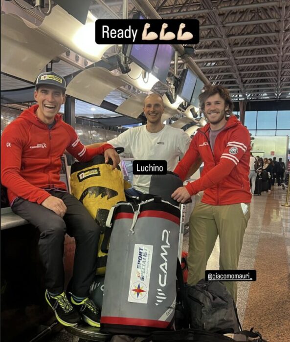 Climbers around a trolley loaded with expedition duffer bags at an airport.