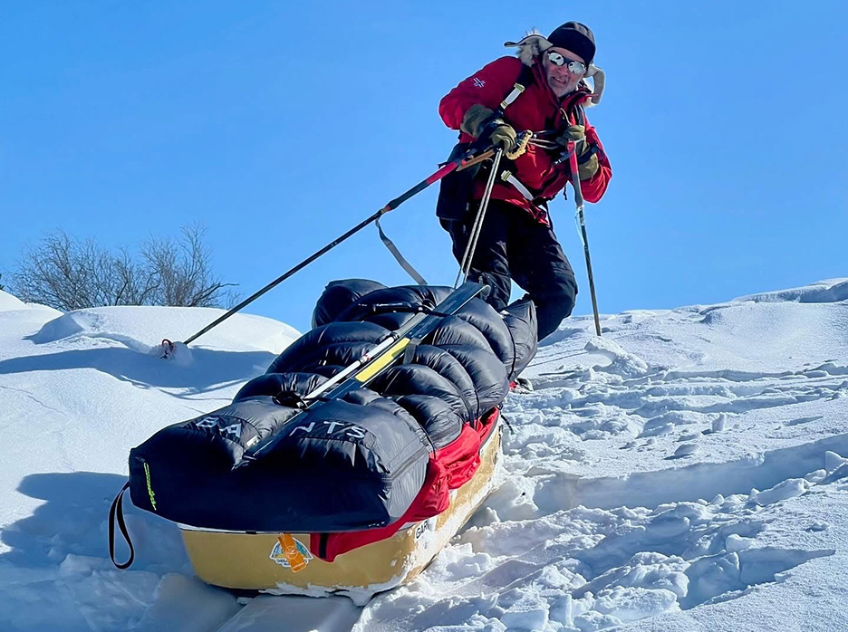 man hauls sled up a steep slope